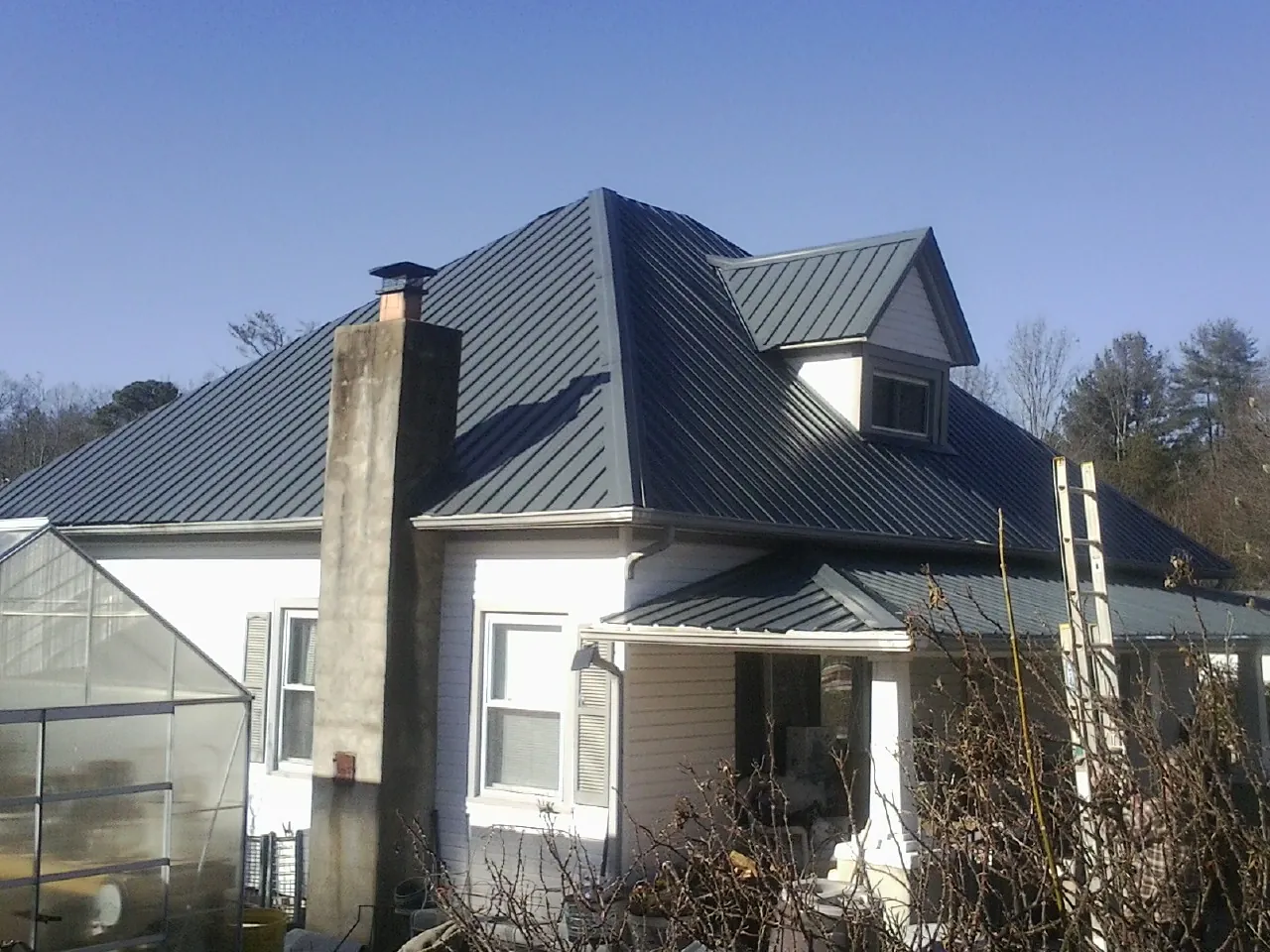 Dark blue standing seam metal roof on a white farmhouse with dormer — Slate & Tile Roof Repair by Roofing Brothers in Sloatsburg