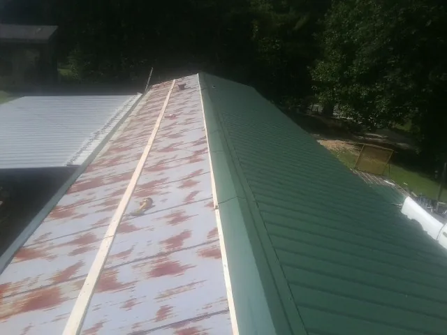 Old rusted panels beside newly installed green metal roofing — Wind Damage Roof Repair by Roofing Brothers in Sloatsburg