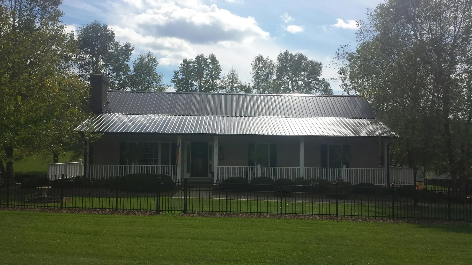 Gray metal roof on a brick ranch with a full width front porch — Gutter Guard Installation work by our crew in Sloatsburg
