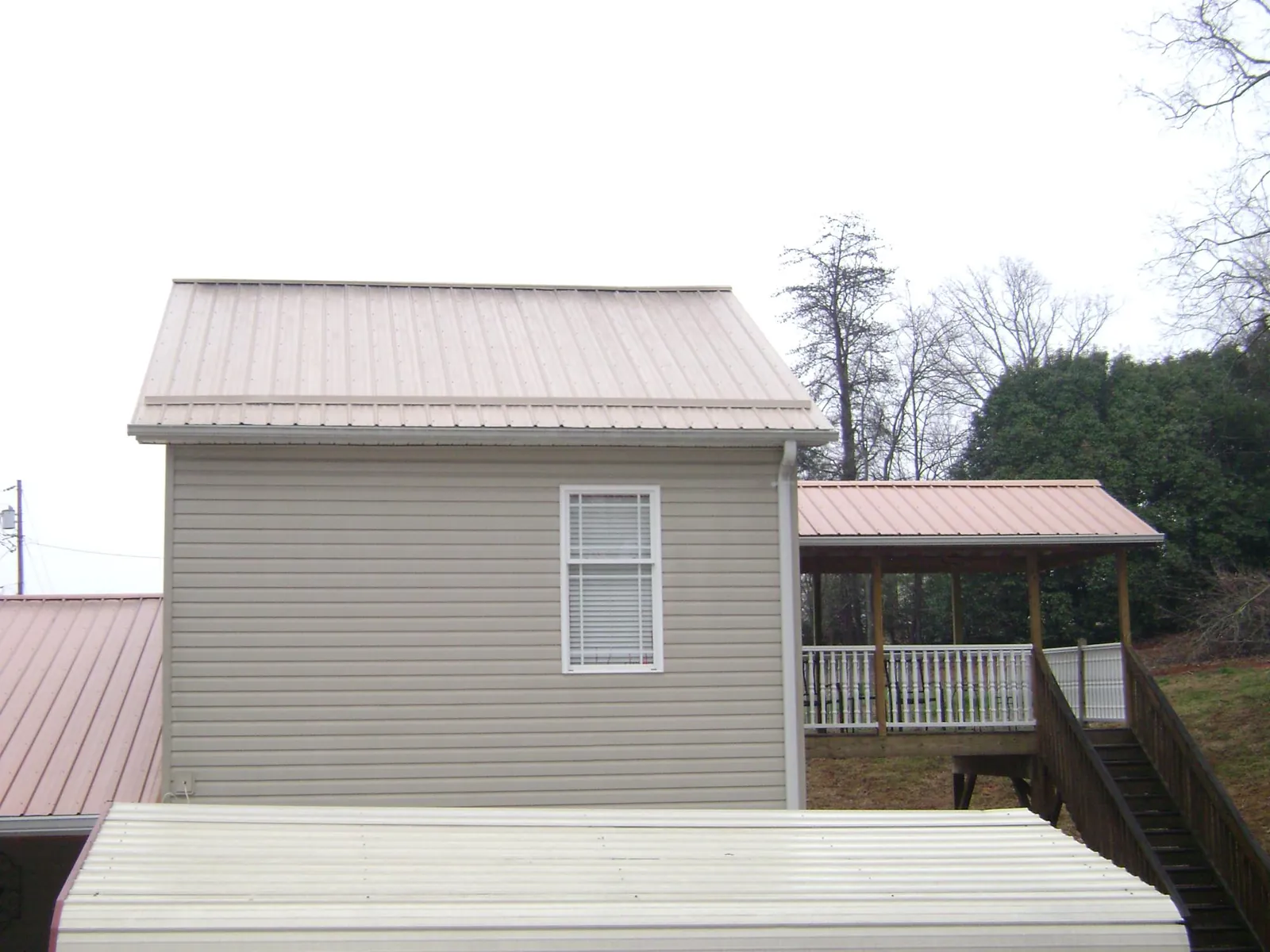 Tan metal roofs on a two story addition and attached porch, from a Roof Replacement job in Sloatsburg